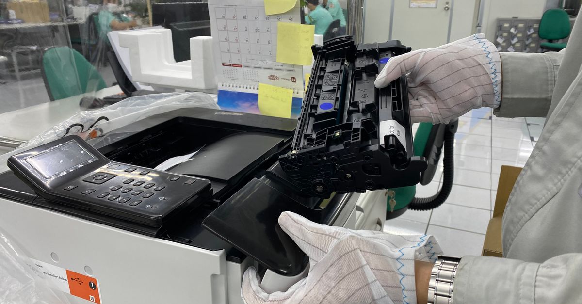 Person mit Schutzhandschuhen setzt eine Tonerkartusche in einen Laserdrucker ein